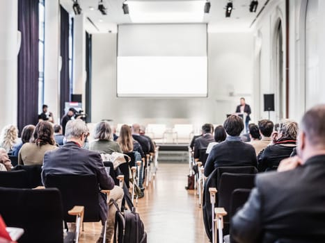 Speaker giving a talk in conference hall at business event. Rear view of unrecognizable people in audience at the conference hall. Business and entrepreneurship concept