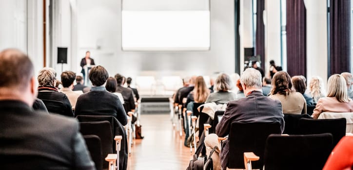 Speaker giving a talk in conference hall at business event. Rear view of unrecognizable people in audience at the conference hall. Business and entrepreneurship concept