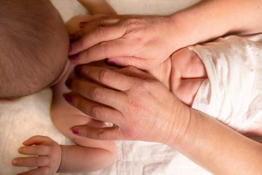 baby back massage. The hands of an adult - a mother or a masseur - massage a little girl. Dark background