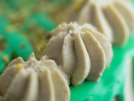 studio shot of green pistachio frosted dripped icing cup cake