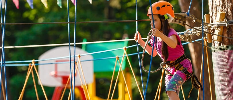 happy little girl in a rope park on the wood background.