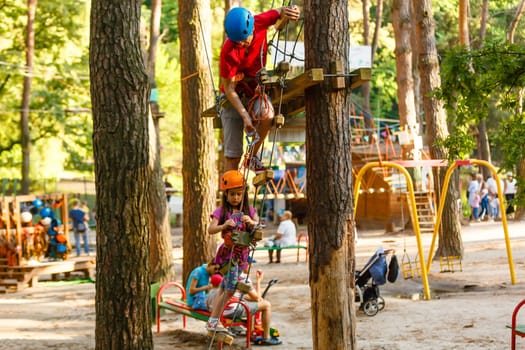 Young father helping his little daughter in the rope park