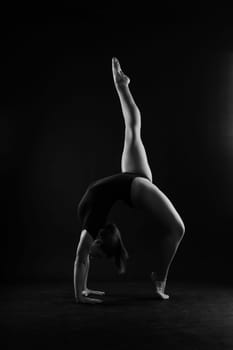 Flexible girl, rhythmic gymnastic artist jumping on white dark background. Grace in motion, action.