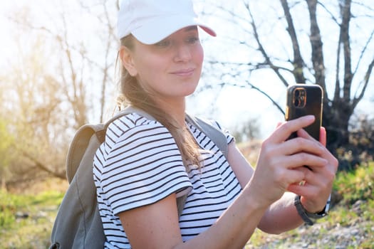 Happy woman traveler with backpack taking selfie during trekking trip in forest.