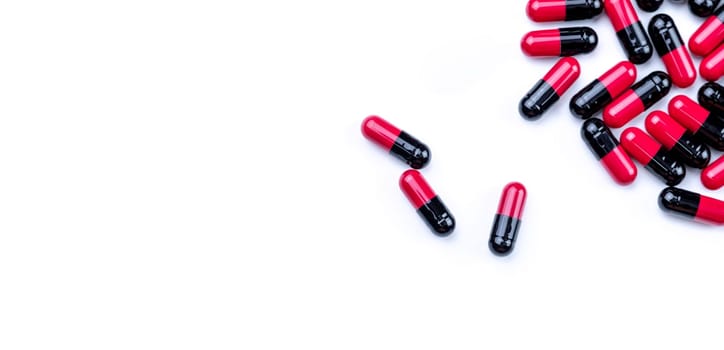 Top view red-black antibiotic capsule pills on white background. Prescription drug. Antibiotic drug. Pharmaceutical industry. Antimicrobial pills for treatment infections. Healthcare and medicine.