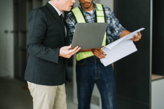 multi ethnic engineer brainstorming and measuring for cost estimating on blueprint and floor plan drawings about design architectural and engineering for houses and buildings.