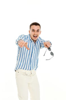 young man in sunglasses and blue striped shirt pointing finger at you isolated on white background.