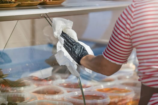 Cleaning and care of glass showcases. A woman cleans a glass showcase in a supermarket. Copy space. High quality photo