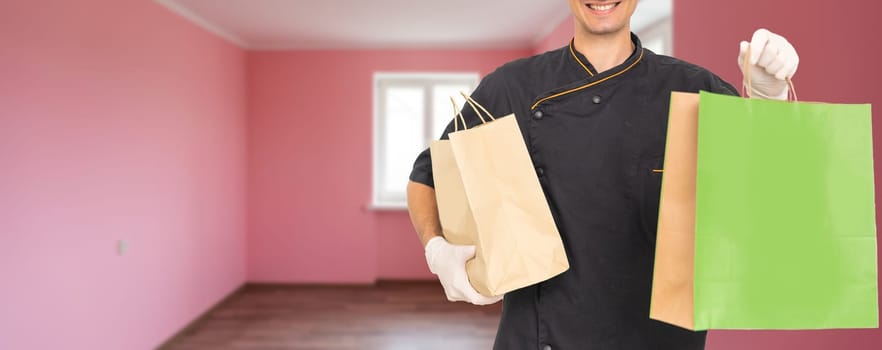 Courier holding paper bags with food, space for text. Delivery service.