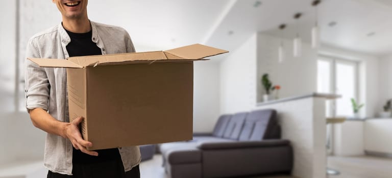 enthusiastic young man carrying cardboard box, moving out of home.