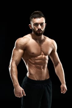 Muscular bodybuilder guy doing posing over black background.