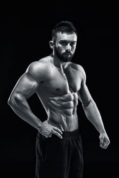 Muscular bodybuilder guy doing posing over black background. Black and white color
