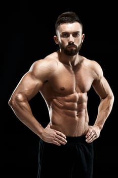 Muscular bodybuilder guy doing posing over black background.