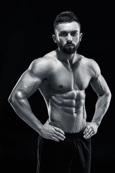 Muscular bodybuilder guy doing posing over black background. Black and white color
