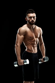 Muscular bodybuilder guy doing posing over black background. dumbbells in his hands. doing exercises