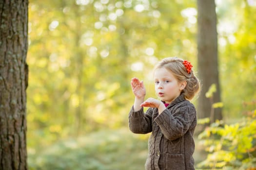 Young happy and smiling mom with her little daughter in arms hugging and kissing spending a weekend on a walk in autumn park.