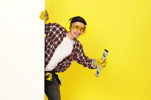 smiling professional builder in work clothes in helmet with level . copy space for text