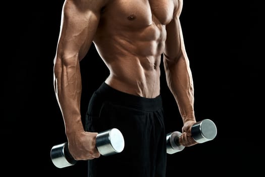 Muscular bodybuilder guy doing posing over black background. dumbbells in his hands. doing exercises. close up