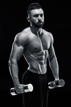 Muscular bodybuilder guy doing posing over black background. dumbbells in his hands. doing exercises . Black and white color