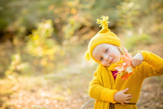 Young happy and smiling mom with her little daughter in arms hugging and kissing spending a weekend on a walk in autumn park.