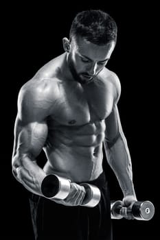 Muscular bodybuilder guy doing posing over black background. dumbbells in his hands. doing exercises. Black and white color