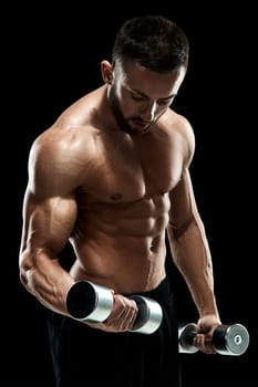 Muscular bodybuilder guy doing posing over black background. dumbbells in his hands. doing exercises