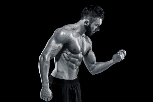 Muscular bodybuilder guy doing posing over black background. dumbbells in his hands. doing exercises. Black and white color