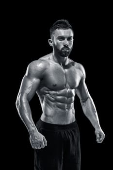 Muscular bodybuilder guy doing posing over black background.. Black and white color