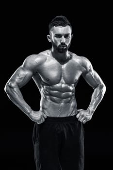 Muscular bodybuilder guy doing posing over black background.. Black and white color