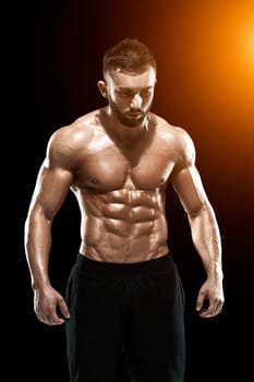 Muscular bodybuilder guy doing posing over black background.. with sun flare