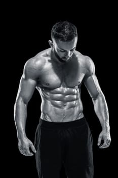 Muscular bodybuilder guy doing posing over black background.. Black and white color