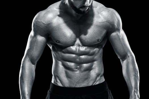 Muscular bodybuilder guy doing posing over black background. Close up. Black and white color