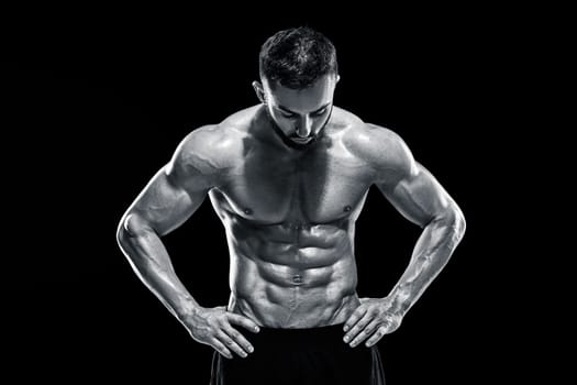 Muscular bodybuilder guy doing posing over black background.. Black and white color