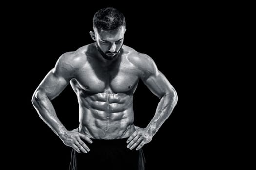 Muscular bodybuilder guy doing posing over black background. Black and white color