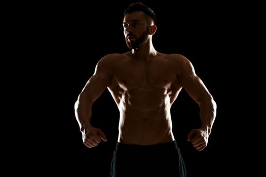 Muscular bodybuilder guy doing posing over black background.