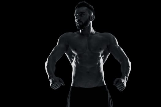 Muscular bodybuilder guy doing posing over black background. Black and white color