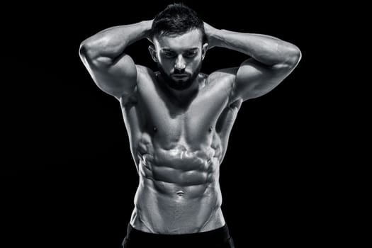 Muscular bodybuilder guy doing posing over black background. Black and white color