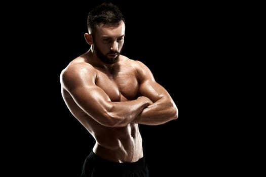 Muscular bodybuilder guy doing posing over black background.