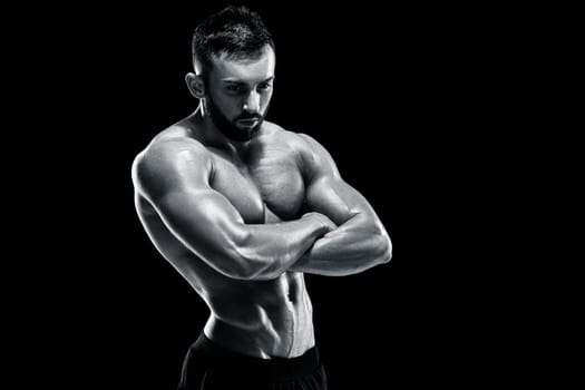 Muscular bodybuilder guy doing posing over black background. Black and white color