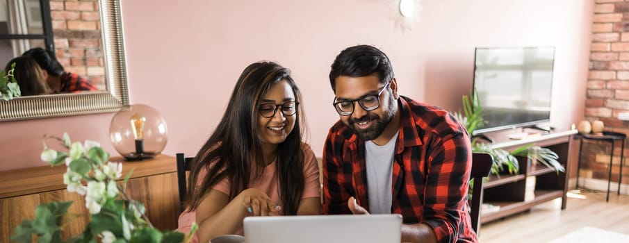 Latino or indian man and woman couple use their laptop in the living room to make video calls. Video call and online chat with familys