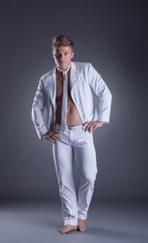 Sexy muscular dancer posing in studio, on gray background