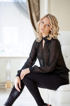 Portrait of young elegant blond posing on white sofa