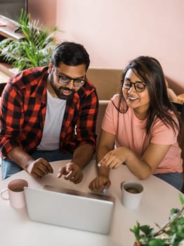 Latino or indian man and woman couple use their laptop in the living room to make video calls. Video call and online chat with familys