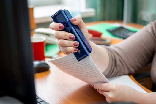 Detail of female hands holding a stapler and filling it with the staples. Focus on the fingers and the staples