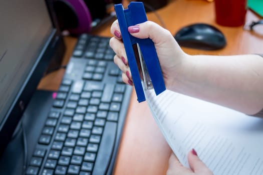 Detail of female hands holding a stapler and filling it with the staples. Focus on the fingers and the staples