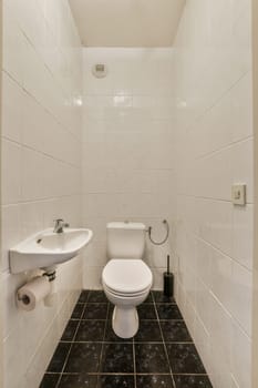 a small bathroom with black and white tiles on the floor, sink and toilet in the wall is made of marble