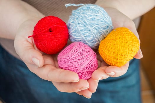 female hands holding stitching, yarn, ingrain, thread in the form of heart close up. materials for handmade and handiwork - sewing, embroidery, knitting.