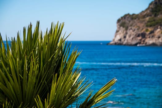 Beautiful summer panoramic seascape. View of the coastline into the sea bays with crystal clear azure water. In the backlight sunbeam light.