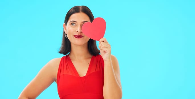 Paper heart, happy woman and face on blue background, studio and backdrop. Portrait of female model in red dress with shape of love, trust and romance for valentines day, flirting and elegant smile.