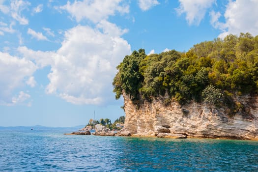 Overview of Isolated Deserted Sand Beach Along Rocky Cliff Lined Coast with Turquoise Waters on Coast of Ibiza, Spain on Sunny Day with Yachts in Distance